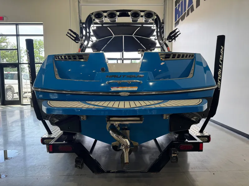 Slide: The Image of Rear view of a blue 2014 Nautique Super Air Nautique 230 boat indoors. - 6