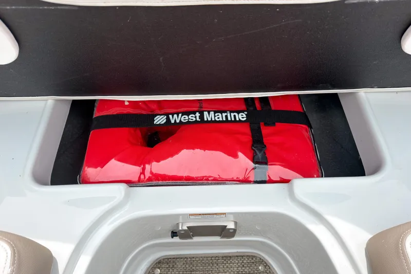 Slide: The Image of Red West Marine life jacket stored in a 2018 Crownline Eclipse E215 XS boat compartment. - 17