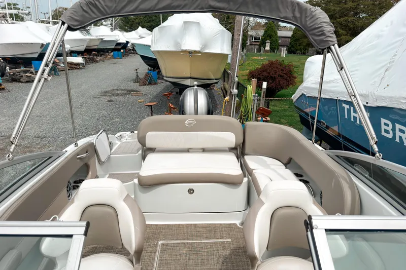Slide: The Image of 2018 Crownline Eclipse E215 XS boat interior with seating, parked in a marina. - 6