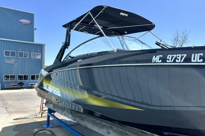 Slide: The Image of 2017 Scarab 255 H.O. Impulse boat docked near a blue building under clear skies. - 3