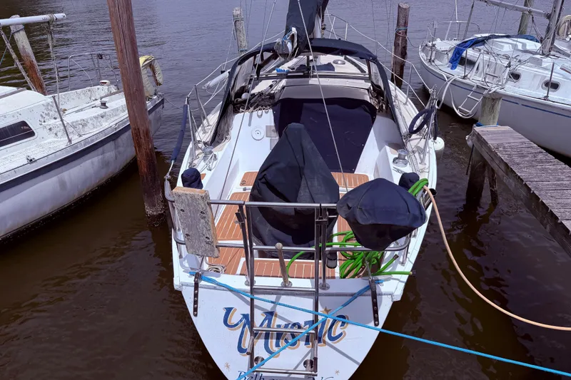 Slide: The Image of Sailboat docked at marina, CAL 31 model from 1981, with covered cockpit and wooden deck. - 2
