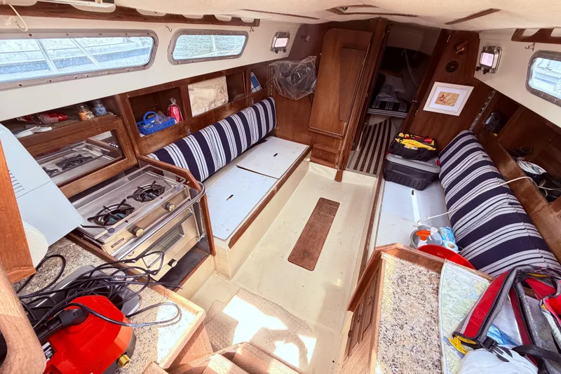 Slide: The Image of Interior of 1981 CAL 31 sailboat with striped seating, stove, and wooden cabinetry. - 20