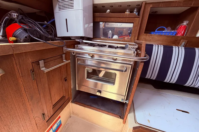 Slide: The Image of Compact kitchen area in a 1981 CAL 31 sailboat with stove and wooden cabinetry. - 24