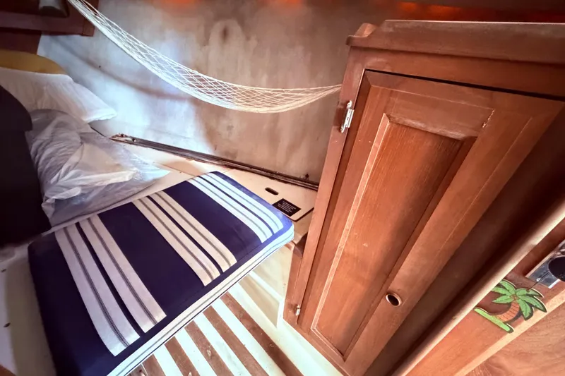 Slide: The Image of Interior of 1981 CAL 31 sailboat with striped cushion, wooden cabinet, and hammock. - 34
