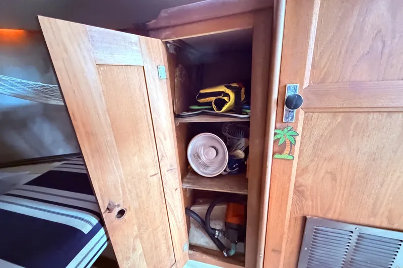 Slide: The Image of Wooden cabinet with open door, revealing shelves with various items inside a 1981 CAL 31 boat. - 35