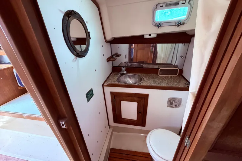 Slide: The Image of 1981 CAL 31 sailboat bathroom with sink, toilet, and porthole window. - 40