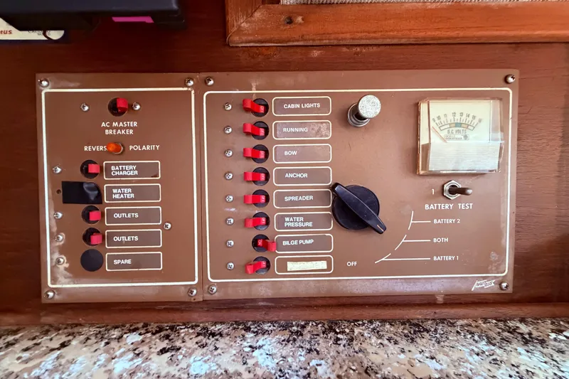 Slide: The Image of Electrical control panel on a 1981 CAL 31 sailboat, featuring switches and battery test gauge. - 49