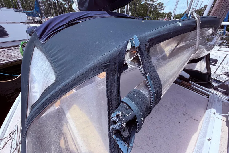 Slide: The Image of Damaged canvas cover on a 1981 CAL 31 sailboat, showing torn fabric and zippers. - 7