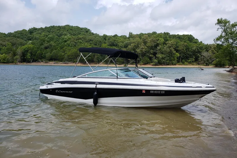 The Image of 2016 Crownline 225 SS boat anchored on a scenic lake with lush green trees. - 0
