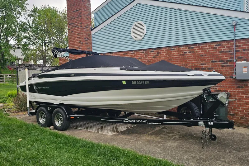 Slide: The Image of 2016 Crownline 225 SS boat on trailer, parked beside a brick house. - 2
