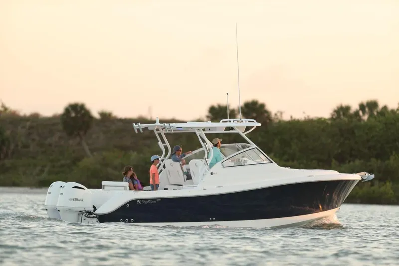 The Image of 2025 Edgewater 280 CX boat cruising on calm water at sunset. - 0