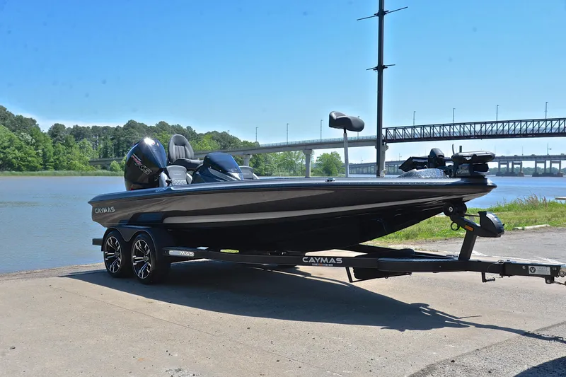 Slide: The Image of 2022 Caymas CX 20 boat on trailer by a river, bridge in background. - 15