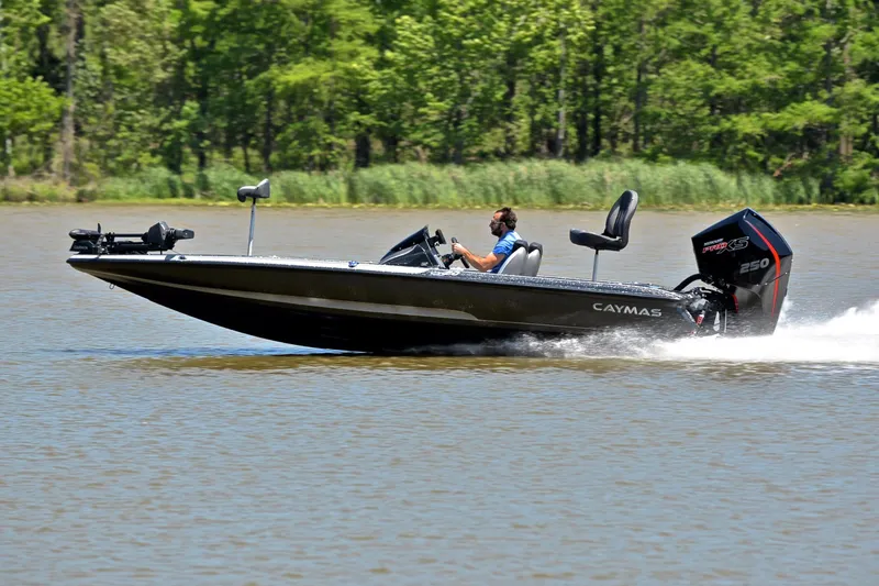 Slide: The Image of 2022 Caymas CX 20 boat speeding on a lake with lush green trees in the background. - 2
