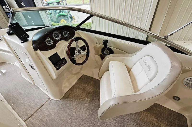 Slide: The Image of 2012 Sea Ray 200 Sundeck cockpit with steering wheel and white captain's chair. - 11