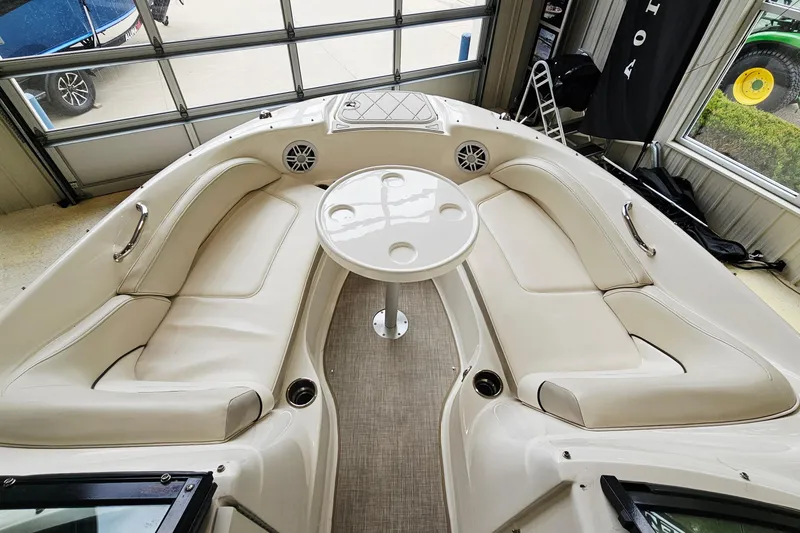 Slide: The Image of 2012 Sea Ray 200 Sundeck interior with beige seating and round table. - 14