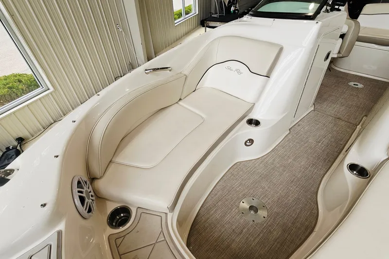 Slide: The Image of 2012 Sea Ray 200 Sundeck interior with beige seating and carpeted flooring. - 16
