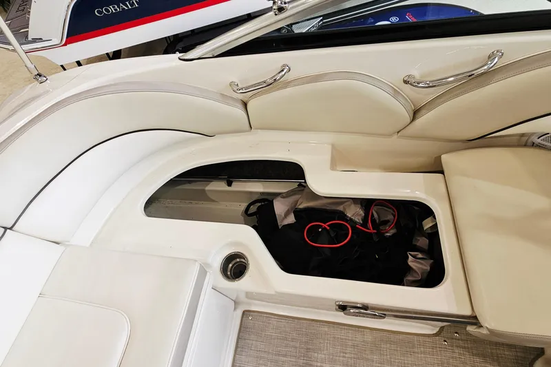 Slide: The Image of 2012 Sea Ray 200 Sundeck interior storage compartment with white seating and red cables. - 22