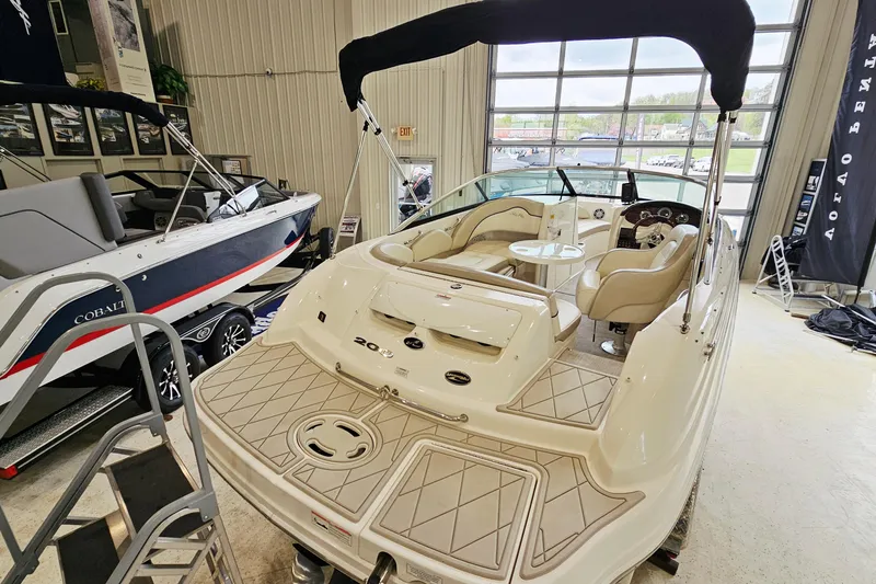 Slide: The Image of 2012 Sea Ray 200 Sundeck boat displayed indoors with seating and canopy. - 5