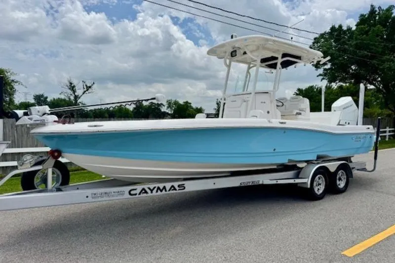 The Image of 2023 Caymas 26 HB boat on trailer, light blue hull, parked on road. - 1