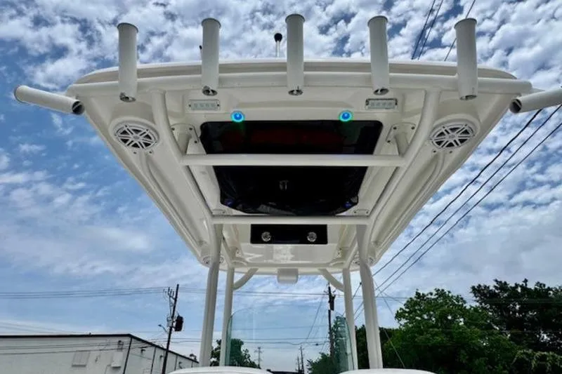 Slide: The Image of 2023 Caymas 26 HB boat top view with rod holders and speakers against a cloudy sky. - 12