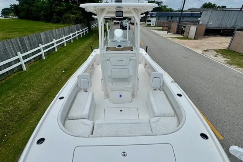 Slide: The Image of 2023 Caymas 26 HB boat with spacious deck and seating, parked on a road. - 17
