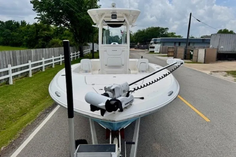 Slide: The Image of 2023 Caymas 26 HB boat on trailer, parked on a road with green surroundings. - 7