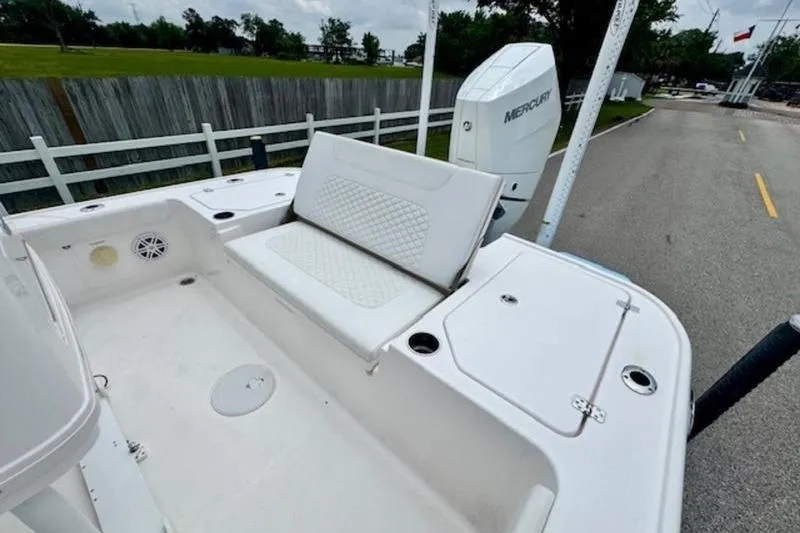 Slide: The Image of 2023 Caymas 26 HB boat with white seating and Mercury engine, parked on a road. - 8