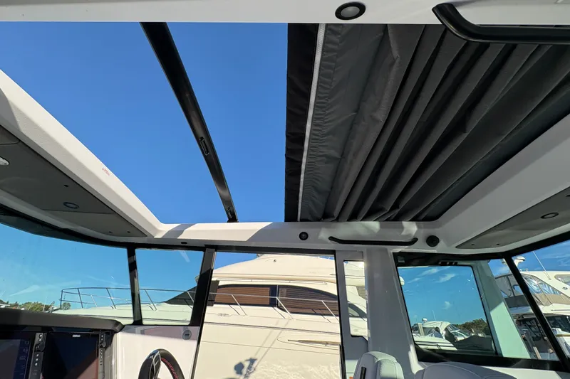 Slide: The Image of Interior view of 2026 Axopar 29 XC Cross Cabin with open sunroof and clear blue sky. - 20
