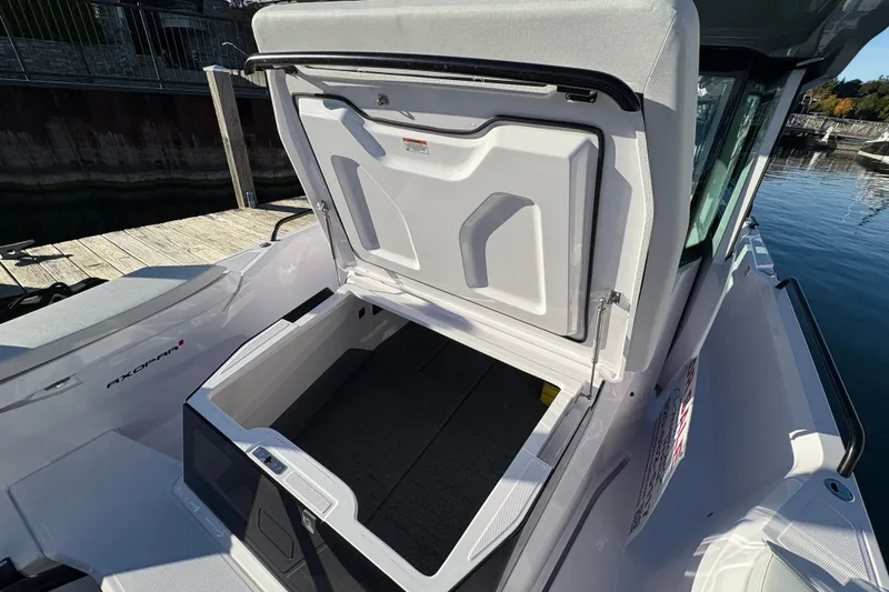 Slide: The Image of 2026 Axopar 29 XC Cross Cabin with open storage compartment at dockside. - 23