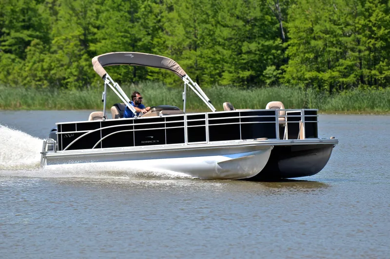 The Image of 2019 Bennington 22 pontoon boat cruising on a lake with lush green trees. - 1