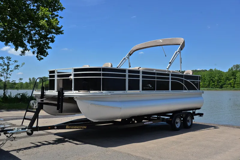 Slide: The Image of 2019 Bennington 22 pontoon boat on trailer by a lake under clear blue sky. - 10