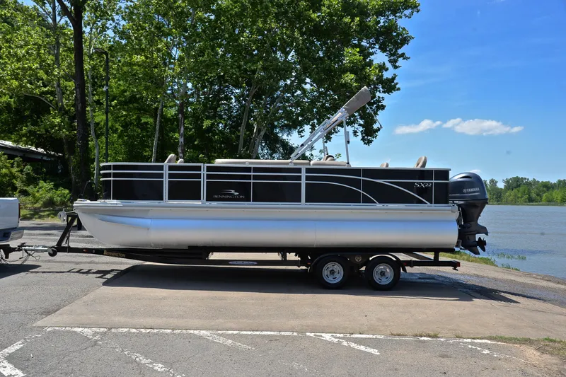 Slide: The Image of 2019 Bennington 22 pontoon boat on trailer by a lake, surrounded by trees. - 11