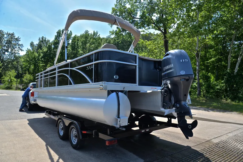 Slide: The Image of 2019 Bennington 22 pontoon boat on trailer with Yamaha 115 engine, parked near trees. - 12
