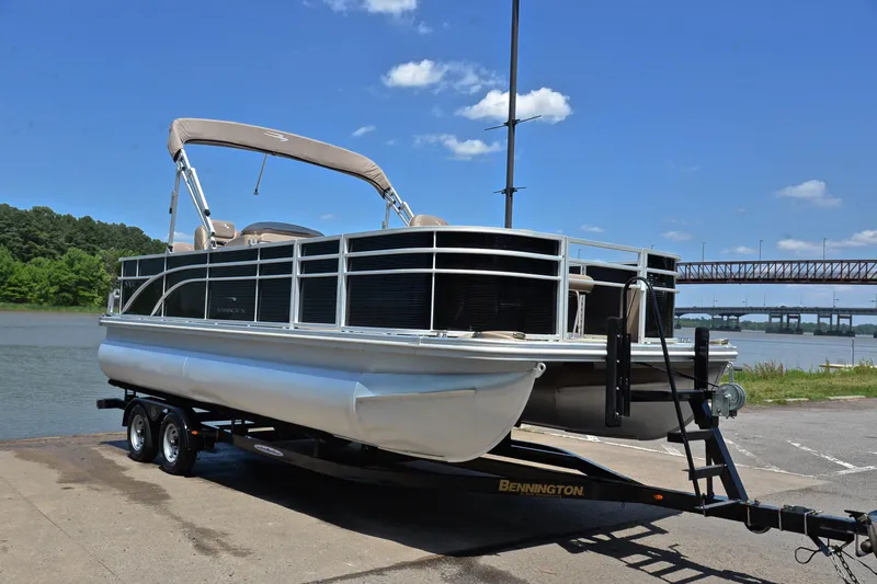 Slide: The Image of 2019 Bennington 22 pontoon boat on trailer by a river under a clear blue sky. - 16