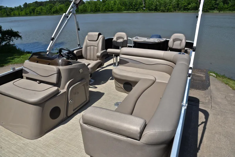 Slide: The Image of 2019 Bennington 22 pontoon boat interior with plush seating by a serene lake. - 22