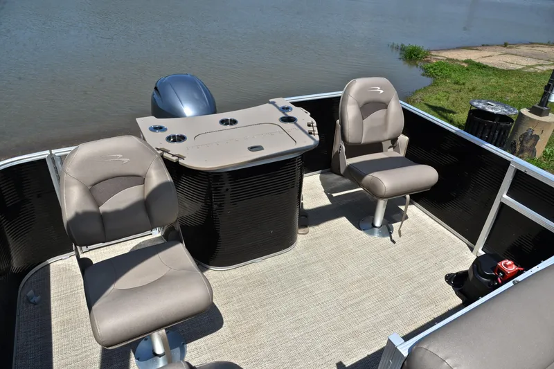 Slide: The Image of 2019 Bennington 22 pontoon boat interior with seating and console by the water. - 24