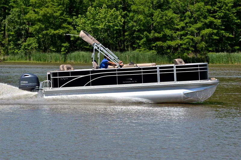 Slide: The Image of 2019 Bennington 22 pontoon boat cruising on a lake with lush green trees. - 3