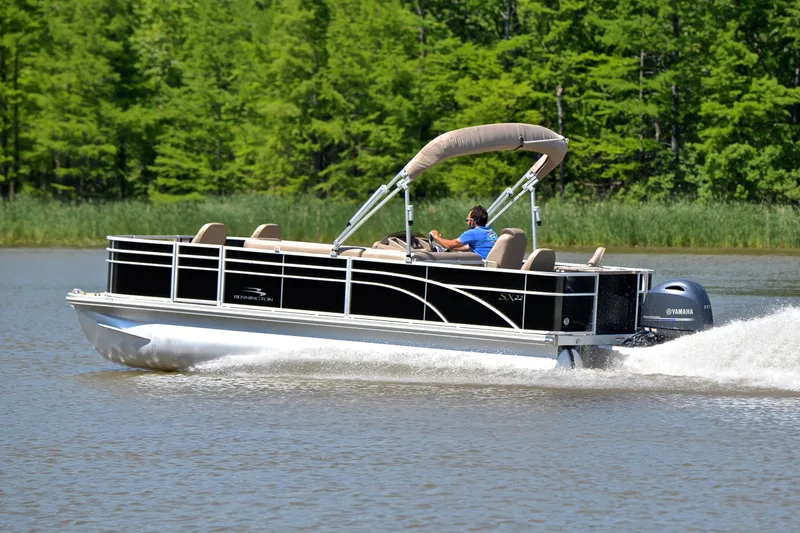 Slide: The Image of 2019 Bennington 22 pontoon boat cruising on a lake with lush green trees. - 4