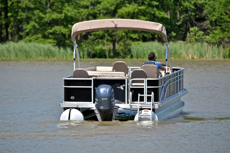 Slide: The Image of 2019 Bennington 22 pontoon boat cruising on a lake with lush green surroundings. - 7