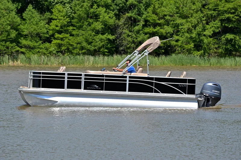 Slide: The Image of 2019 Bennington 22 pontoon boat cruising on a lake with lush green trees. - 8
