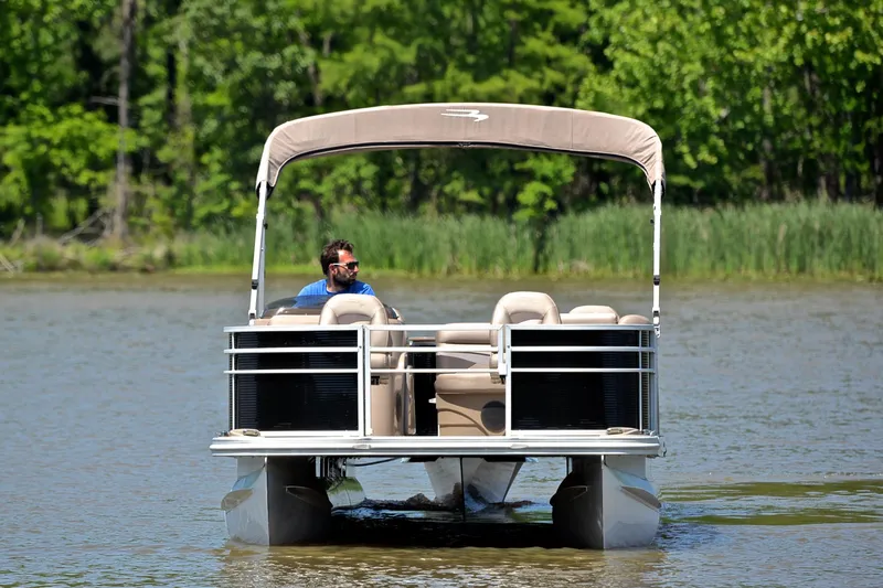 Slide: The Image of 2019 Bennington 22 pontoon boat cruising on a lake with lush green background. - 9