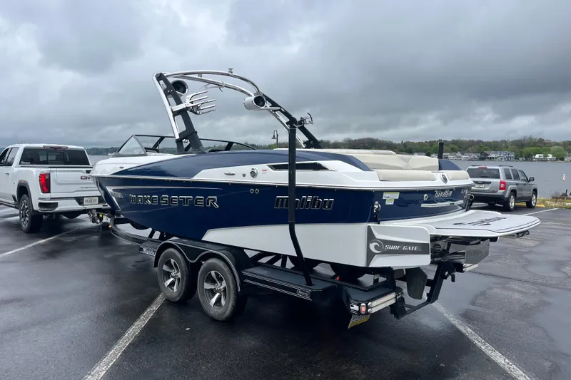 Slide: The Image of 2014 Malibu Wakesetter 23 LSV boat on trailer, parked near a lake on a cloudy day. - 10