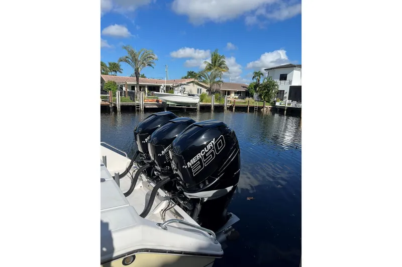 Slide: The Image of 2010 Venture 39 Open boat with triple Mercury 350 engines docked by waterfront homes. - 2