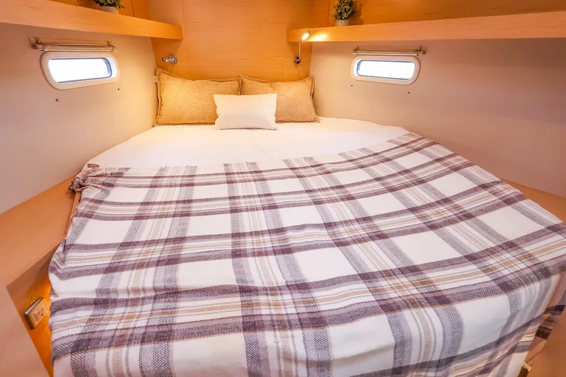 Slide: The Image of Cozy cabin interior of 2026 Hanse 360 yacht with plaid bedding and porthole windows. - 3