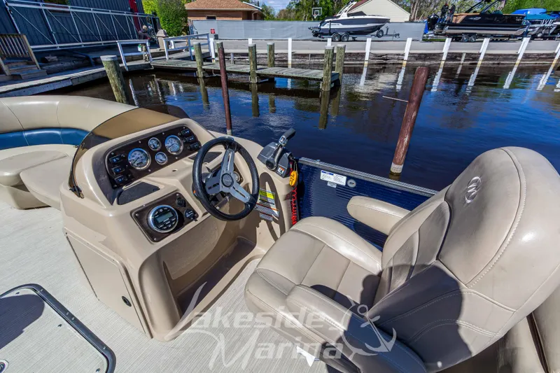 Slide: The Image of 2018 Manitou Aurora 23 LE RF VP boat interior with steering console and plush seating. - 14