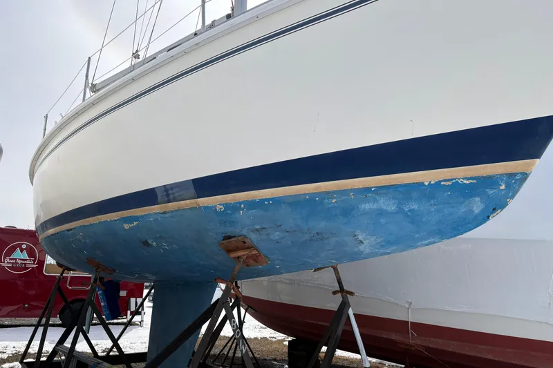 Slide: The Image of 1988 Pearson 28 sailboat on stands, showing blue hull and white upper section. - 1