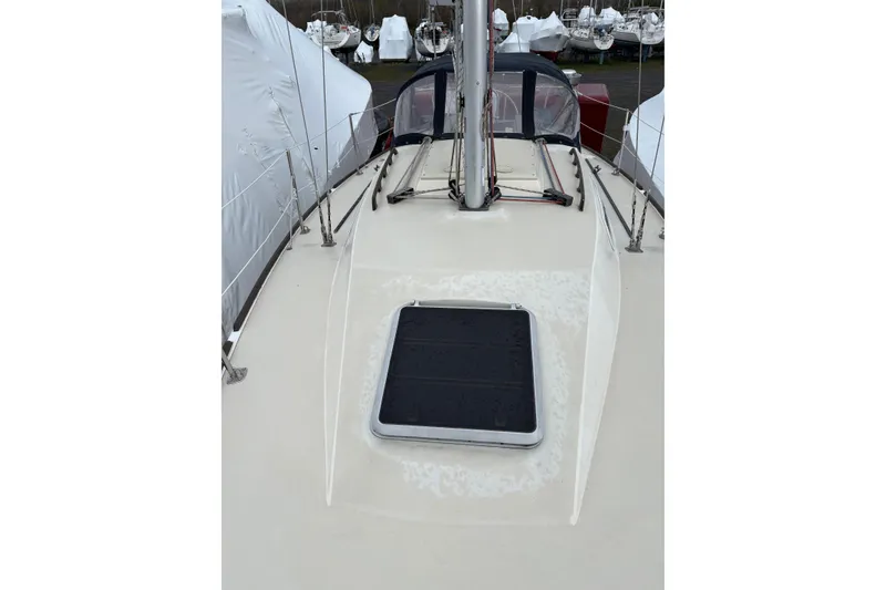 Slide: The Image of 1988 Pearson 28 sailboat deck with hatch, docked among covered boats. - 13