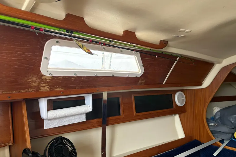 Slide: The Image of Interior of a 1988 Pearson 28 sailboat with wooden paneling and fishing rods. - 19