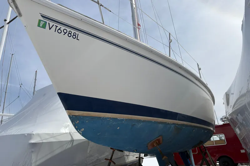 The Image of 1988 Pearson 28 sailboat with blue hull, docked and elevated for maintenance. - 0