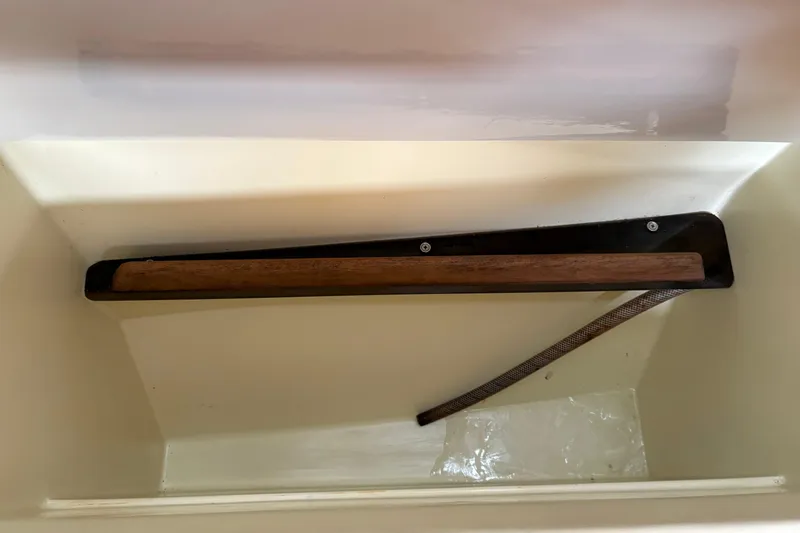 Slide: The Image of Interior view of a 1988 Pearson 28 sailboat, featuring a wooden tiller and storage compartment. - 19
